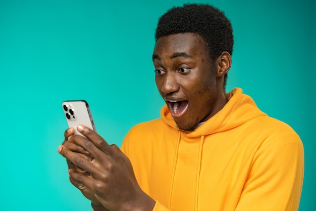 Afro american man using smartphone over isolated mint background