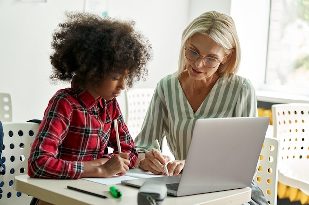 Foto studentessa afroamericana che impara con l'insegnante tutor femminile che utilizza il computer portatile