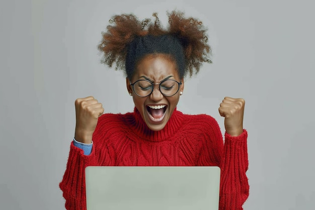 Afro American teenager woman excited and celebrative with laptop yelling and fist in hands contest winner