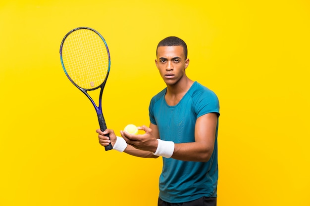 Uomo afroamericano del tennis sopra fondo giallo isolato