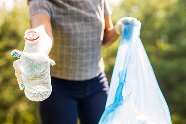 晴れた日に夏の公園でプラスチックゴミを集めるアフリカ系アメリカ人のボランティア