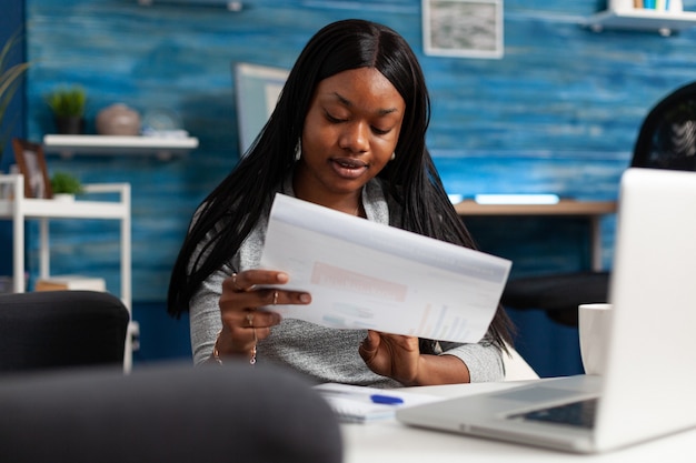 Afro american woman analyzing financial graph document remote working at marketing presentatrion