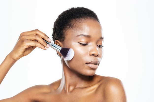 Afro american woman applying makeup with brush isolated on a white background