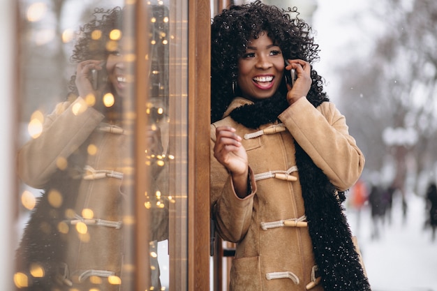 Donna afroamericana con il telefono in inverno