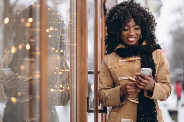 Afro american woman with phone in winter