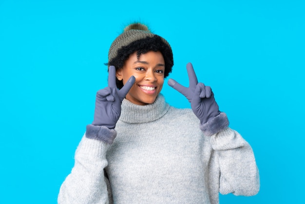 Afro American woman  with winter hat over blue wall