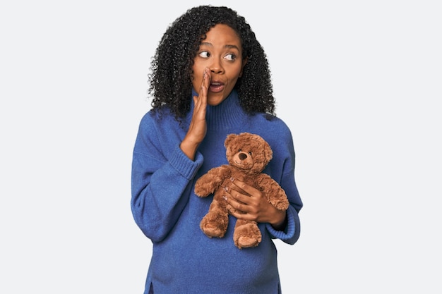 Foto afro-amerikaan met een teddybeer verwachten is een geheim heet remnieuws vertellen en opzij kijken