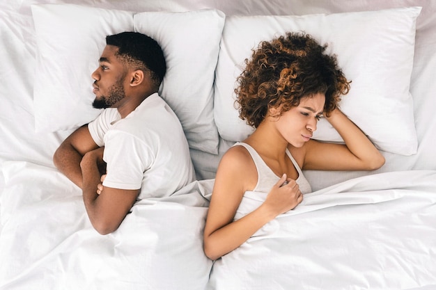 Afro-Amerikaans echtpaar negeert elkaar in bed.