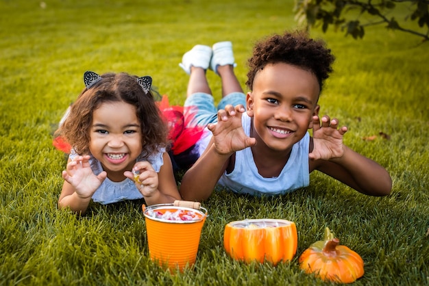 Afro-Amerikaans jongensmeisje verkleed als heks en kattenoren-tovenaar voor Halloween Trick or treat