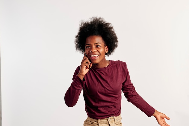 Afro-Amerikaans meisje in bruine trui poseert tijdens een telefoongesprek.