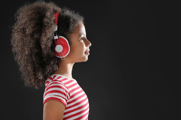 Afro-Amerikaans meisje met koptelefoon op donkere achtergrond