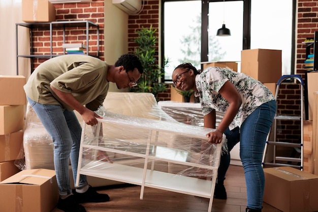 Afro-amerikaans stel dat samen in een nieuw appartement verhuist, meubels uitpakt om het huishouden te versieren. Genieten van verhuizing na het kopen van het eerste huis om een nieuw begin te maken en een levensgebeurtenis te vieren.