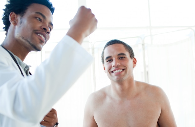 Afro-Amerikaanse arts die de temperatuur van de patiënt controleert