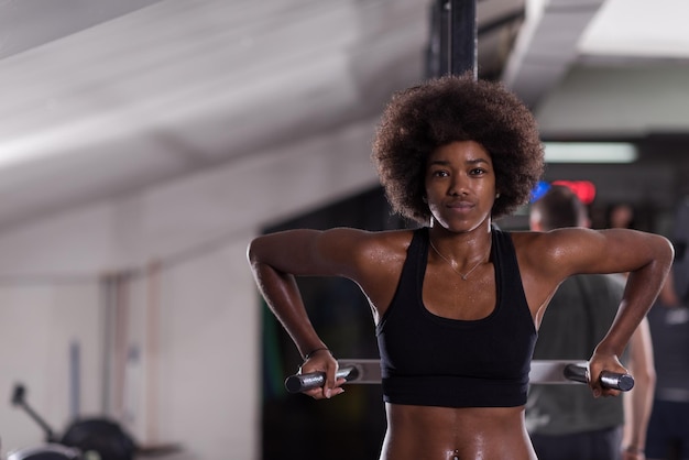 Afro-Amerikaanse atleet vrouw training uit armen op dips horizontale parallelle staven Oefening training triceps en biceps doen push ups