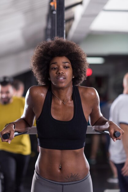 Afro-Amerikaanse atleet vrouw training uit armen op dips horizontale parallelle staven Oefening training triceps en biceps doen push ups