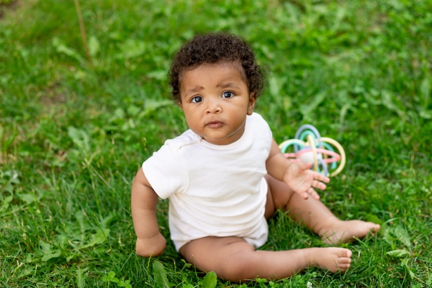 Afro-Amerikaanse babyjongen op het groene grasveld in de zomer spelen, ruimte voor tekst