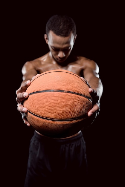 Afro-Amerikaanse basketballer poseren met bal op zwart