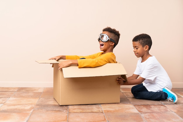 Afro-Amerikaanse broers spelen. Jongen in een kartonnen doos met vliegeniersglazen