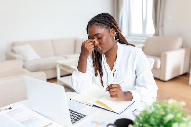 Foto afro-amerikaanse creatieve vrouw die aan het bureau werkt, voelt zich moe gestresst