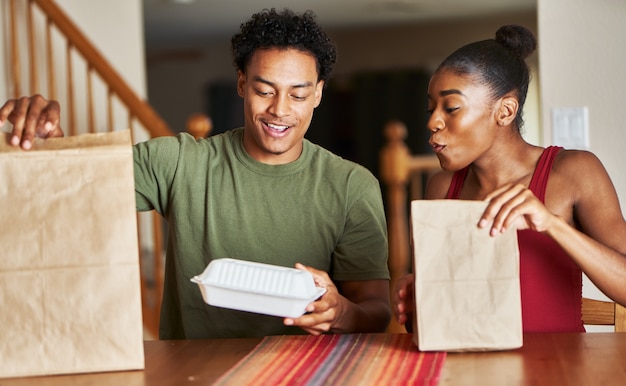 Afro-Amerikaanse echtpaar zittend aan tafel kijken naar voedsel levering