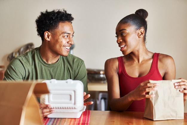 Afro-Amerikaanse echtpaar zittend aan tafel kijken naar voedsel levering