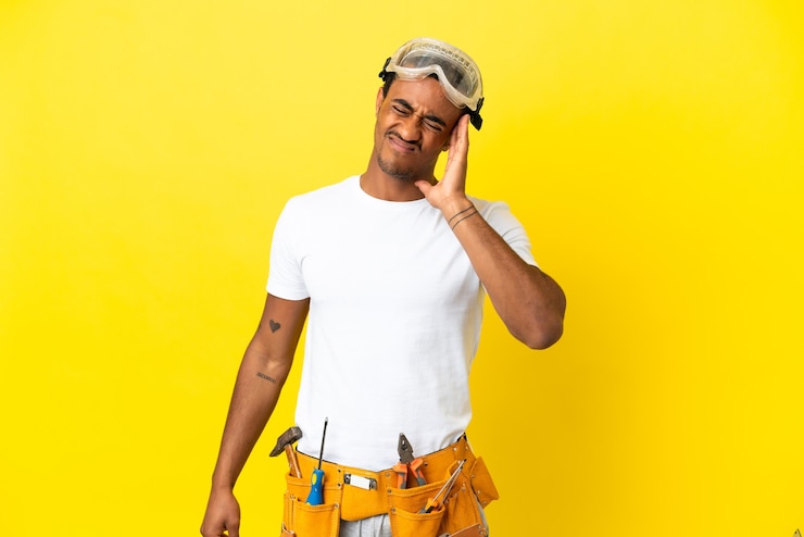 Foto afro-amerikaanse elektricien man over geïsoleerde gele muur met hoofdpijn
