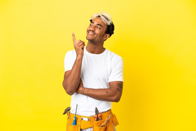 Afro-Amerikaanse elektricien man over geïsoleerde gele muur wijzend op een geweldig idee