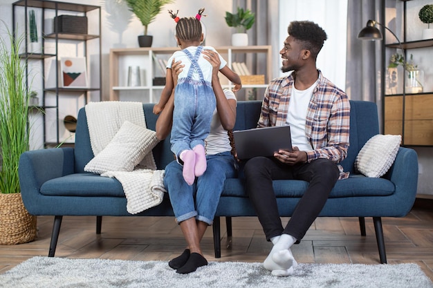 Afro-Amerikaanse familie zittend op de bank met laptop