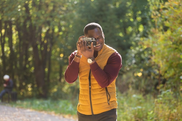 Afro-amerikaanse fotograaf die een foto maakt met een vintage camera op de kopieerruimte l van het stadsgroen park