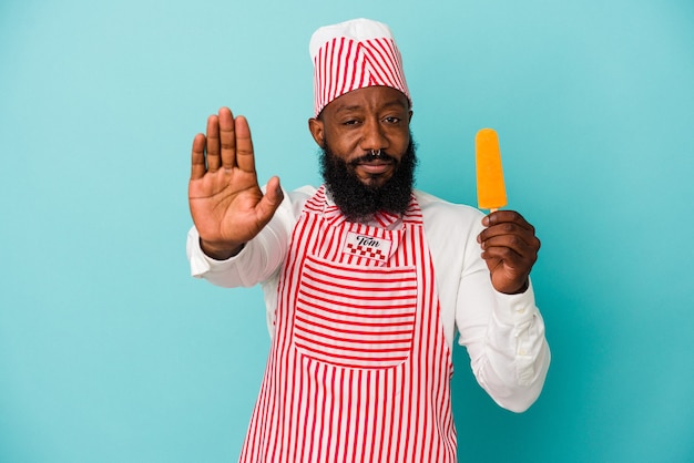 Afro-Amerikaanse ijsmaker man met een ijsje geïsoleerd op blauwe achtergrond staande met uitgestrekte hand weergegeven: stopbord, voorkomen dat u.