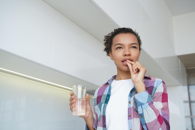 Afro-Amerikaanse jonge meid neemt pillen voor de natuurlijke schoonheid van de huid Wellness gezonde levensstijl