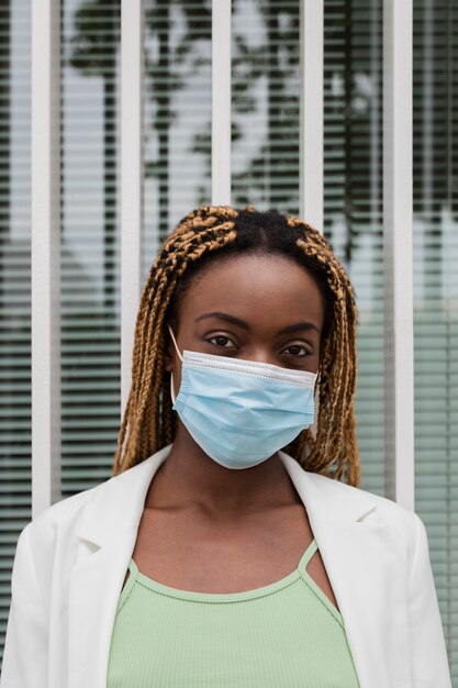 Afro-Amerikaanse jonge vrouw die naar de camera kijkt met een beschermend gezichtsmasker Verticale gezondheidszorg