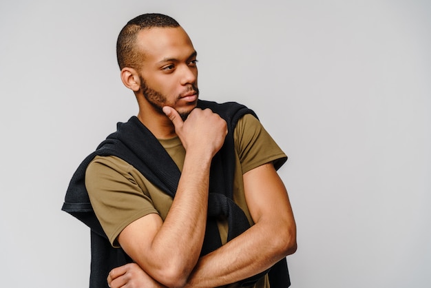 Afro-Amerikaanse jongeman in groen t-shirt over lichtgrijze muur