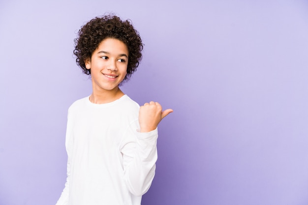 Afro-Amerikaanse jongen wijst met duim vinger weg, lachen en zorgeloos.