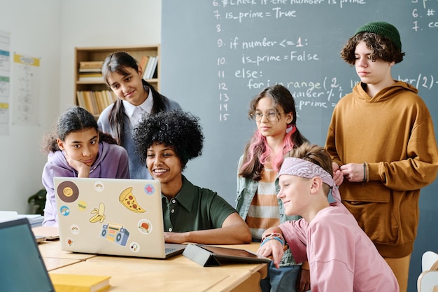 Afro-Amerikaanse leraar die laptop gebruikt om studenten informatietechnologie in de klas te leren