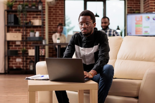 Afro-Amerikaanse man aan het werk op laptop pc om bedrijfspresentatie te plannen met gegevensonderzoek en informatie. Kantoormedewerker die een bedrijfsrapport gebruikt om e-mails te verzenden en administratief papierwerk te doen.