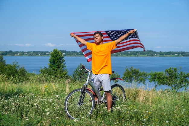 Afro-Amerikaanse man die de Amerikaanse vlag vasthoudt en zwaait en met de fiets staat