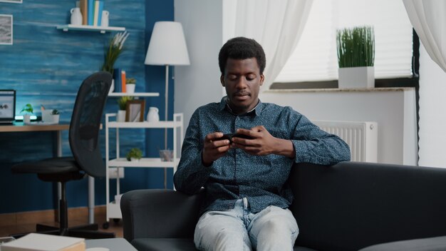 Afro-Amerikaanse man die videogames speelt op zijn telefoon