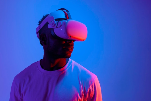 Afro-Amerikaanse man die videospelletjes speelt in een virtuele realiteitsbril in neonverlichting