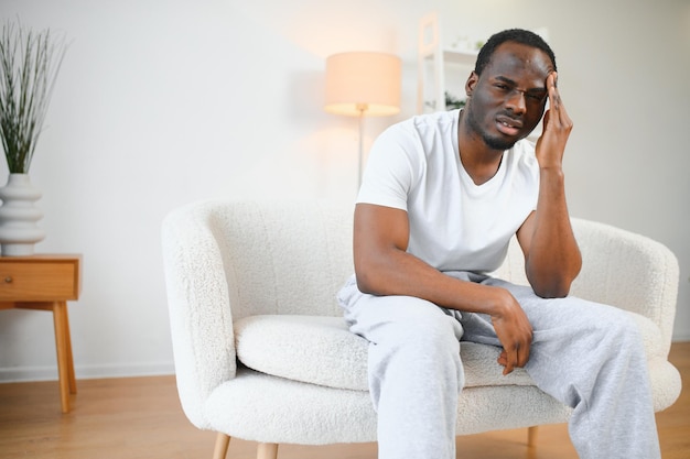 Afro-Amerikaanse man gestrest op de bank thuis.