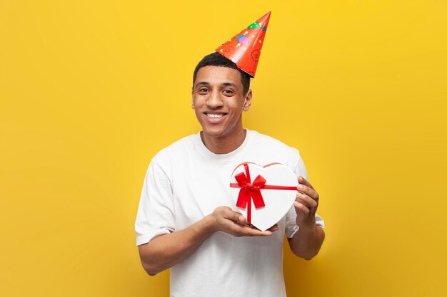 Afro-Amerikaanse man in feestelijke hoed viert zijn verjaardag en houdt geschenk hart man met doos