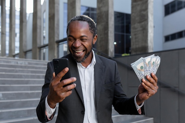 Afro-amerikaanse man in pak verheugt zich dat hij een online lening voor kleine bedrijven heeft gekregen met contant geld