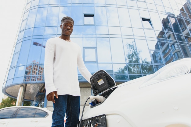 Afro-Amerikaanse man laadt zijn elektrische auto op.