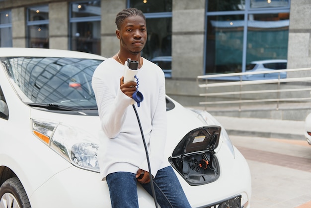 Afro-amerikaanse man laadt zijn elektrische auto op.