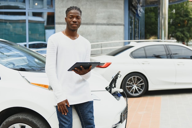 Afro-Amerikaanse man laadt zijn elektrische auto op.