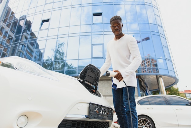 Afro-Amerikaanse man laadt zijn elektrische auto op.