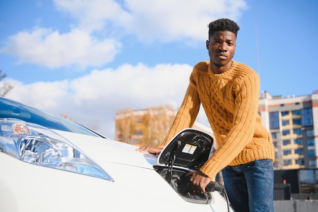 Afro-Amerikaanse man laadt zijn elektrische auto op.