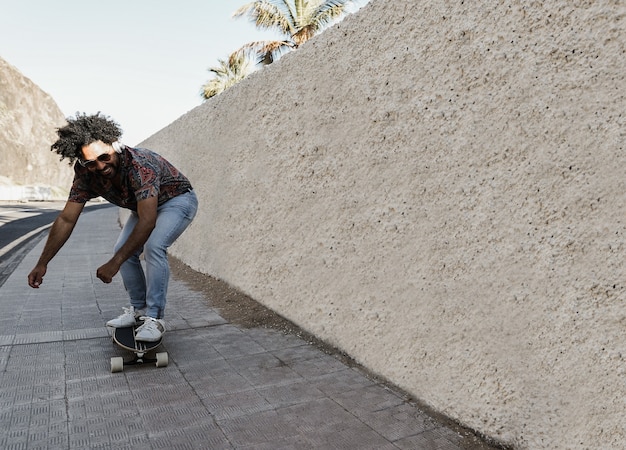 Afro-Amerikaanse man longboard rijden op de weg met palmbomen op de achtergrond - Focus op gezicht