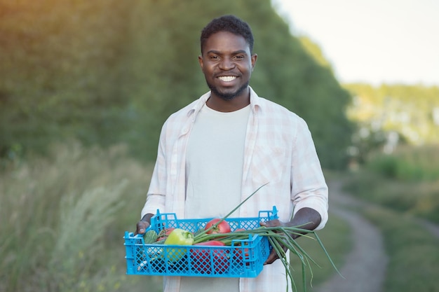 Afro-amerikaanse man loopt met boerderijoogst in doos bij bomen