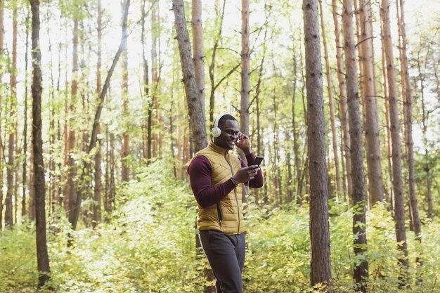 Afro-Amerikaanse man luistert naar muziek in de kopieerruimte van het lentepark en plaats voor de app voor reclamegadgets